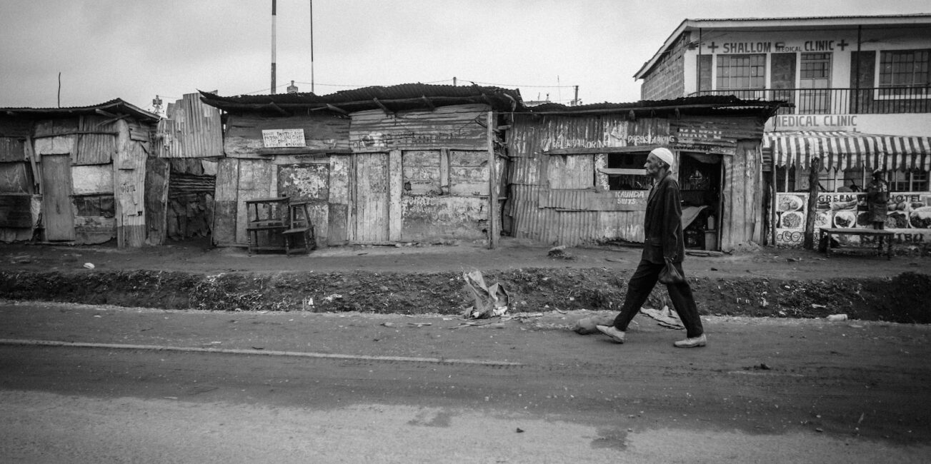 grayscale photo of man walking on road during daytime