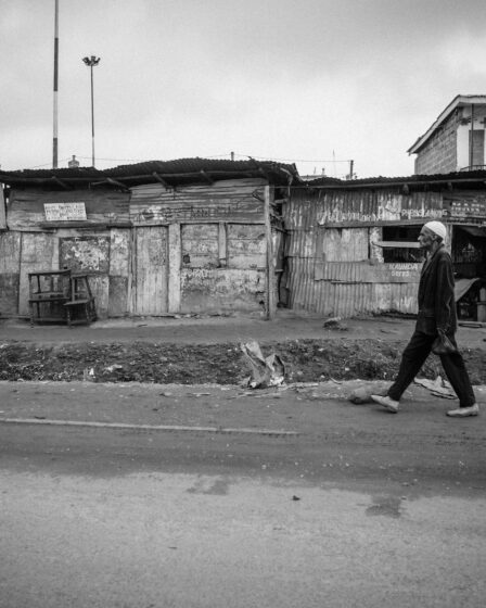 grayscale photo of man walking on road during daytime